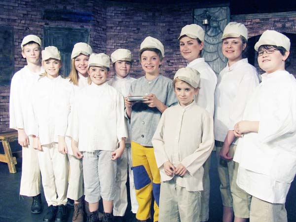 The Orphans, in no particular order, Brandon Carvajal, Charlee Coker, Aubri Donalson, Sarah Michael Farrington, Jonathan Farrington, Annamarie Hall, Chase Harrison, Brooke Phillips, Lucas Reynolds, Alaiya Schuyler, Viviana Schuyler, join Dani Parker (holding the bowl) to sing about “Food, Glorious Food.”
