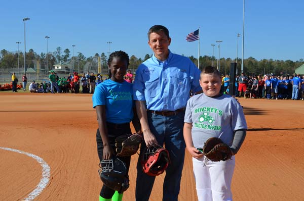 THEY’RE READY TO PLAY, as demonstrated by Desirae Beachem, left, and Dakota Eakin, right, who caught opening baseball and softball pitches thrown by Bainbridge Mayor Edward Reynolds.
