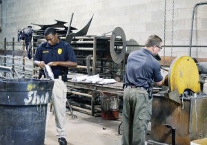 BPS Investigator Anthony Stubbs, left, and BPS Major Robert Humphrey destroy the seized weapons at the city’s shop department.|Submitted photo