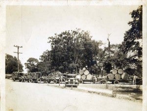 LONG TIME AGO: A load of timber is brought to the Willis Sawmill by long time supplier, J.S. Shoemaker, who is shown to the right of the car wearing a broad brimmed hat. 