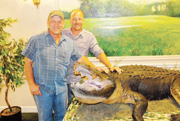 Troy and Jacob Landry, stars of the “Swamp People” television show, stand next to a Lake Seminole alligator measuring 13 feet, nine inches that was on display at the Bainbridge Country Club, where the father and son were meeting fans and signing autographs on Friday. The show airs on the History Channel on Thursday nights.