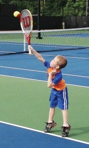 Reece Atkinson stretches his arm up to hit a tennis ball at the Slip, Slide and Serve tennis camp at the Bainbridge Tennis Center.|Brennan Leathers