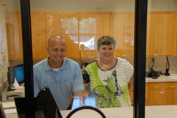Jamie Ard and Tammi Godwin, the interim assistant principal and interim principal at John Johnson Elementary, stand behind the sturdy glass that separates the school’s main office from its lobby, part of a new secure entrance recently installed at the school.