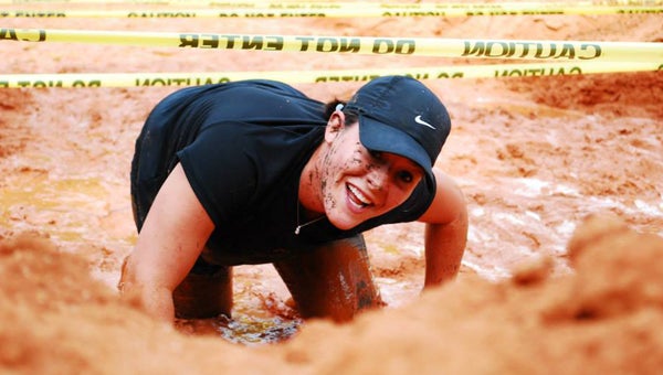 Volunteer Melody Finley crawls under caution tape, moves through mud as she heads to the finish line at the Young Barbarian Mud Run Saturday, hosted by Leisure Services. -- Carol Heard