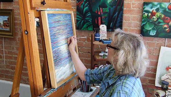 Vickie Bailey, above, paints in her new store downtown Artsy on the Square. Bailey will sell art supplies, gifts and more. 