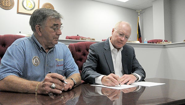 Decatur County Chairman Frank Loeffler (left) and Grady EMS Vice President Bill Compton sign the contract that was voted on at Tuesday’s County Commission meeting.