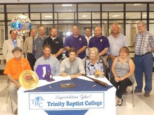 Tyler Braswell signs among family, friends and coaches. In front, from left: Dan Humphrey, Grandfather; Chad Braswell, Dad; Tyler Braswell; Rita Braswell, Mom; Judy Thursby, Aunt. In back: Stanley Phillips, Pastor; Tommie Howell, Principal; Stan Killough, Athletic Director; Blake Cecil, Asst. Coach; Brian McCorkle, Coach; Scott Miller, Asst. Principal; Christopher Bryant, Asst. Coach; Gordon Hutchins, Friend; Ricky Thursby, Uncle.