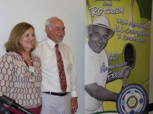 Rotary Club President Threasa Hall and Gene McNease stand beside a life-size poster advertising the tournament. 