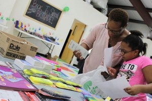 Margo Brenton, left, and her daughter, consult a school supply list while at the YMCA Friday afternoon. 