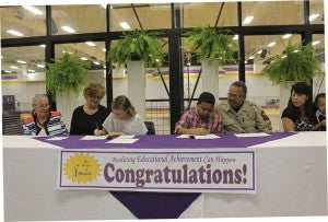 Leigha Sapp, left center, and Yugi Cotton, right center, sign their scholarship agreements with family members.